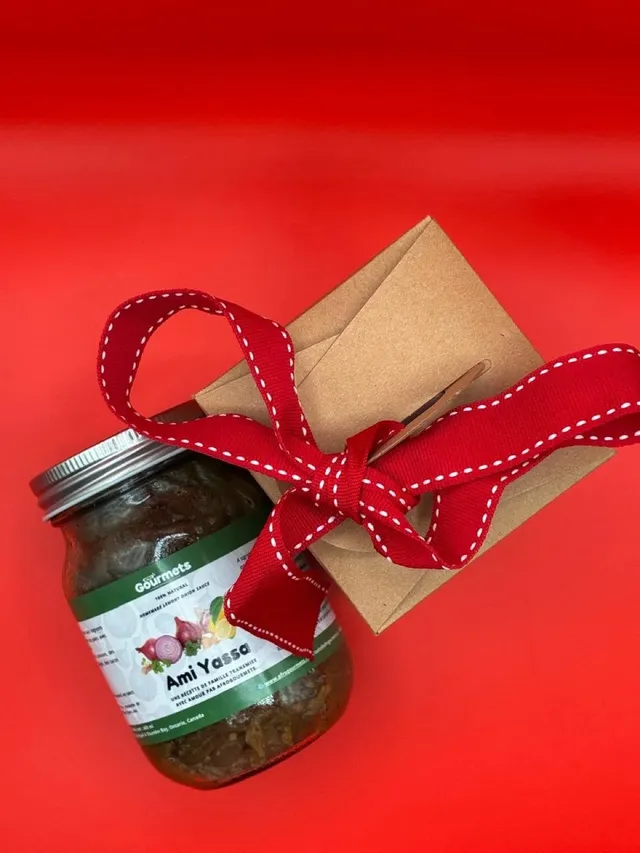 A jar of AfroGourmets Ami Yassa sauce with a gift box tied with red ribbon