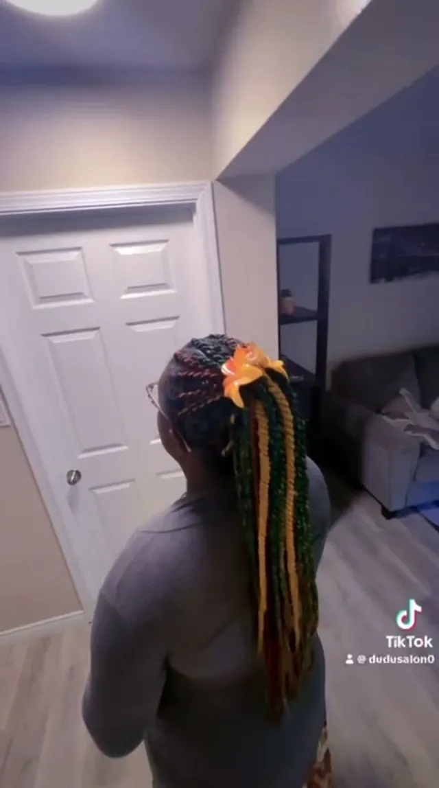 Multicoloured twists in a high ponytail with an orange flower clip