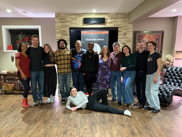 An adult class group smiling together in the Dame Más Dance studio